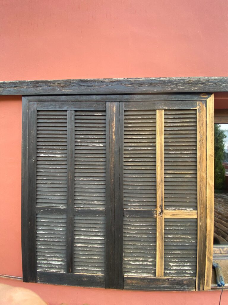Wooden shutters and window restored on a red-walled house