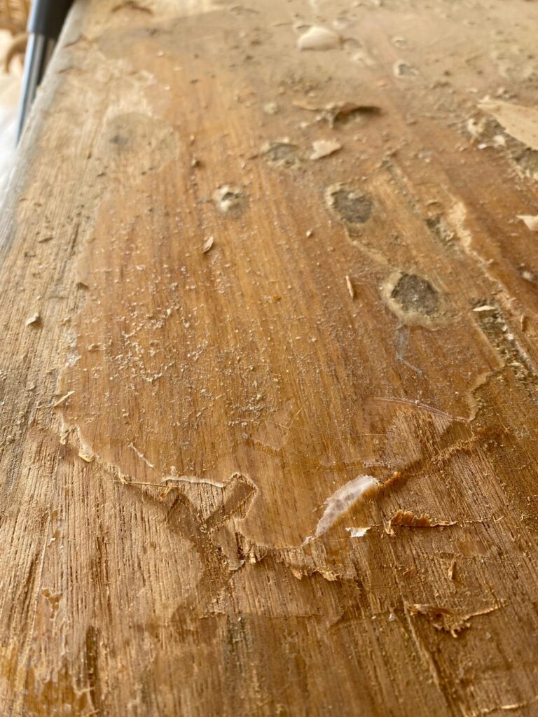 Water-damaged varnish on an iroko table before restoration