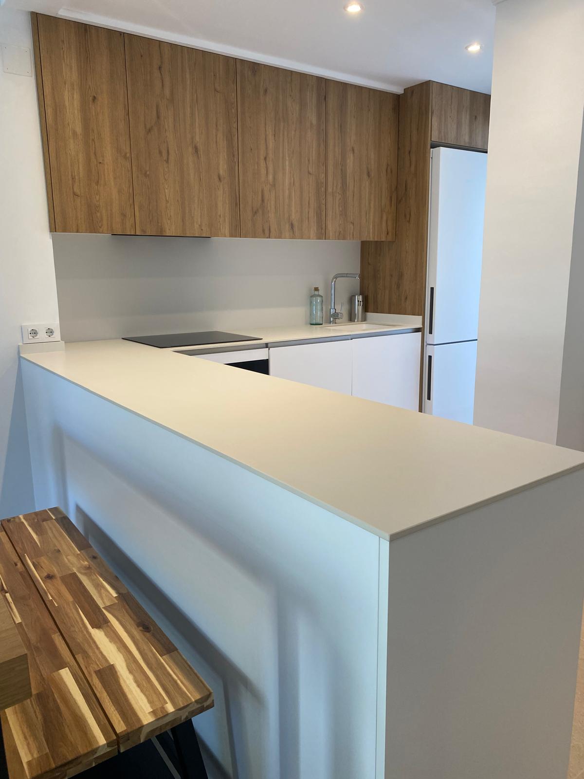 White kitchen with oak cabinets and island in Jávea