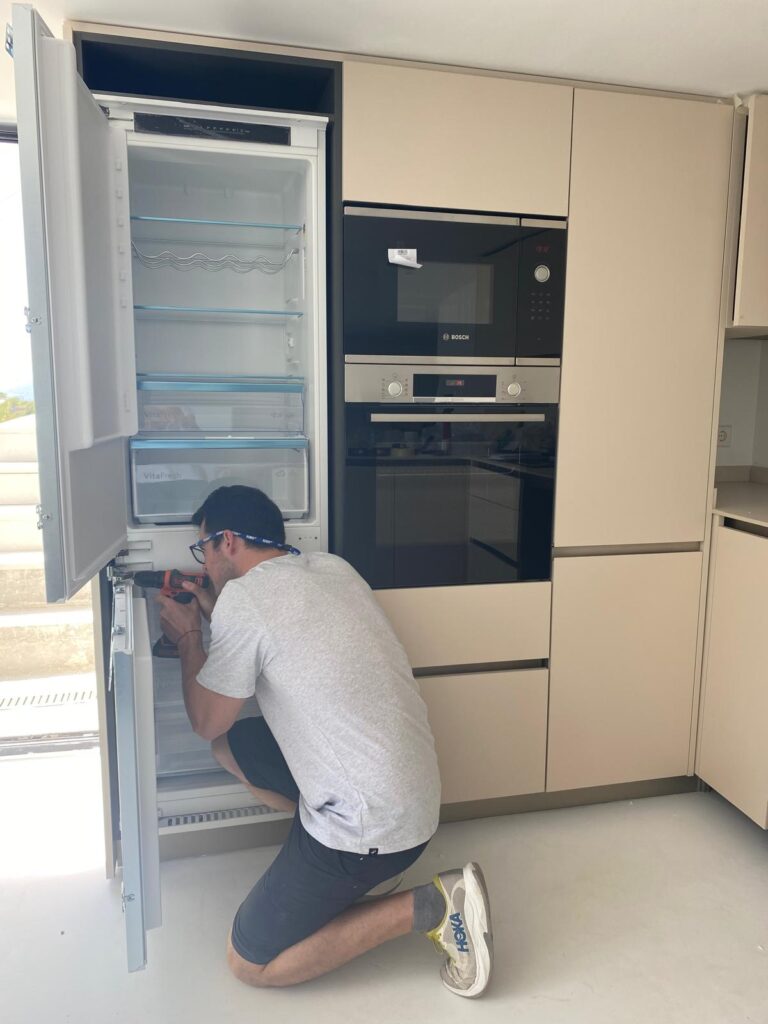 Mauro installing an integrated fridge in a kitchen in Benissa