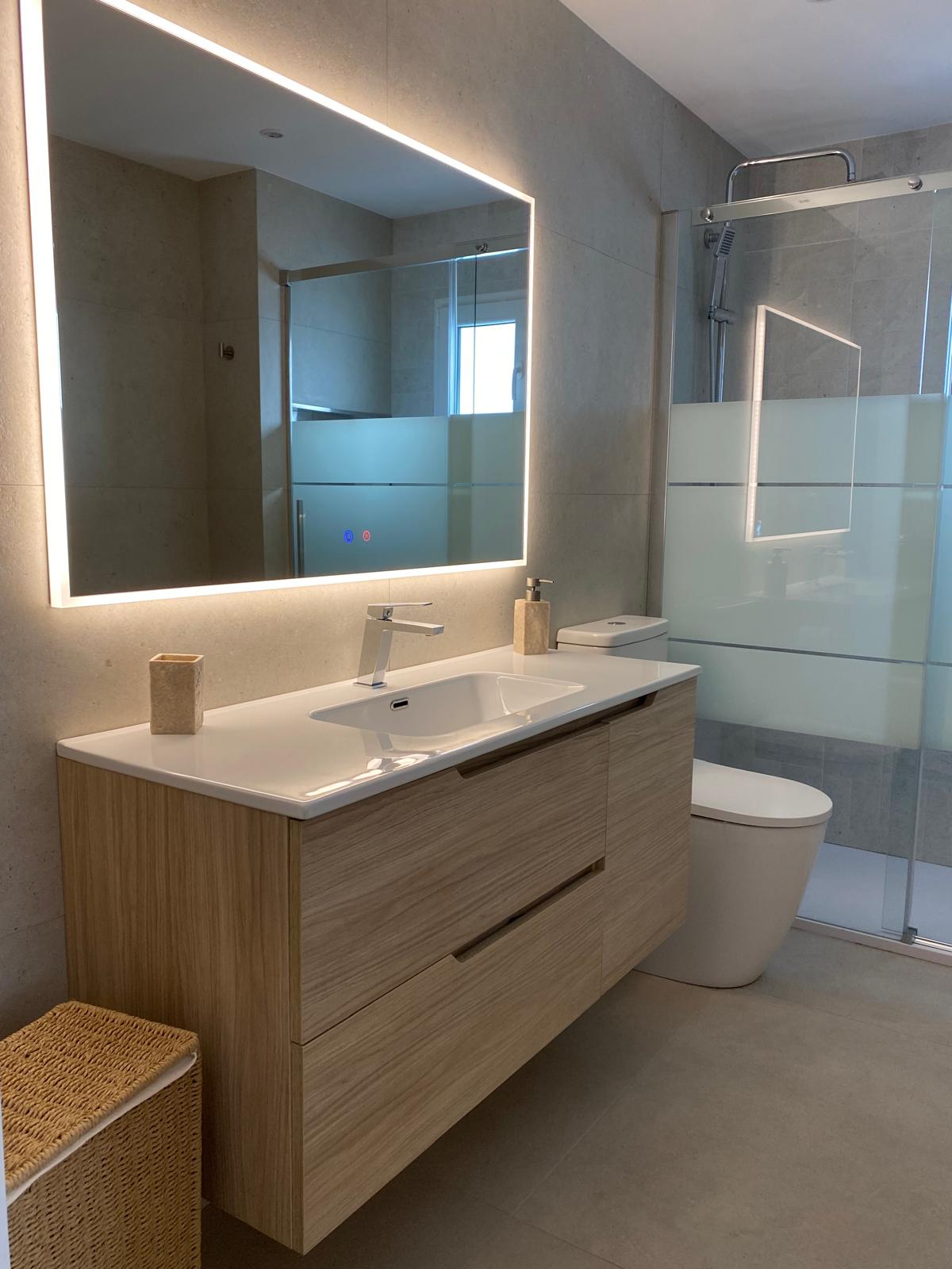 Renovated bathroom with oak vanity, backlit mirror and glass shower screen in Gata de Gorgos