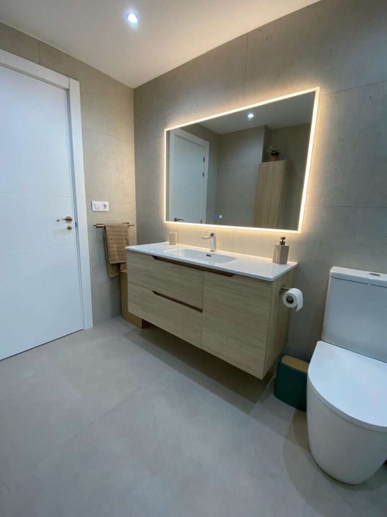 Renovated bathroom with large-format tiles and backlit mirror